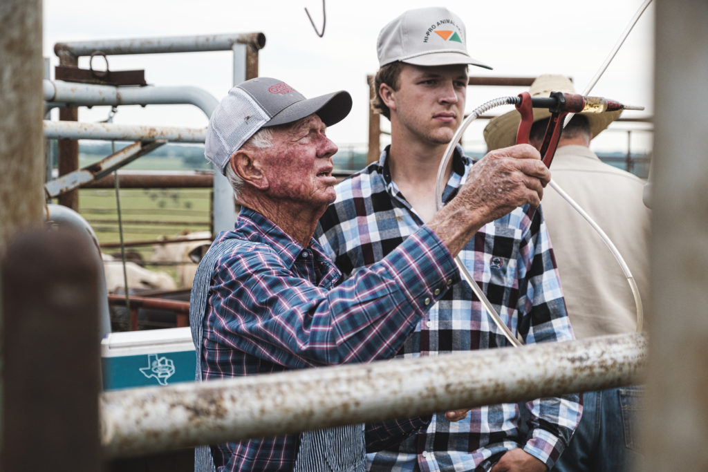 Older rancher showing young rancher how to operate equipment
